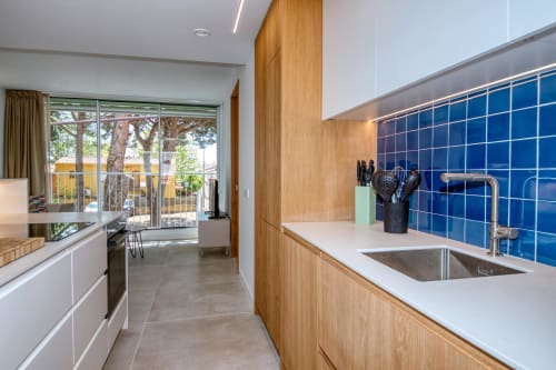 Cocina moderna con azulejos azules, muebles de madera y vistas al patio en Finques Garcia Enrich, Palafrugell