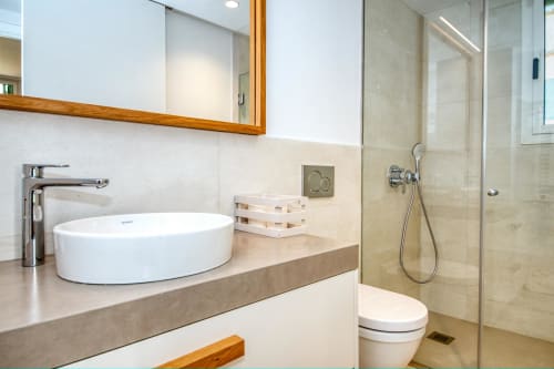 Baño moderno del hotel Finques Garcia Enrich en Palafrugell con lavamanos de cerámica, ducha de cristal y acabados de mármol