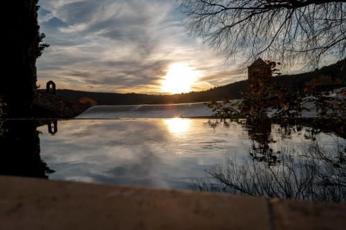 Sonnenuntergang über dem ruhigen See von La Bouscatière, Moustiers-Sainte-Marie mit kahlen Bäumen und Hügeln
