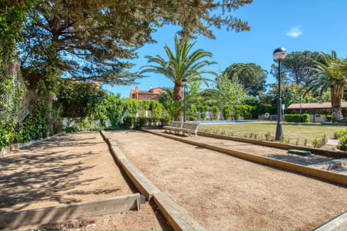 Bocce ball courts at Finques Garcia Enrich in Palafrugell with palm trees and green grounds under clear blue sky