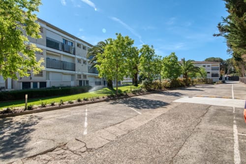 Palafrugell apartment complex courtyard with green landscaping, mature trees, and modern buildings under blue sky