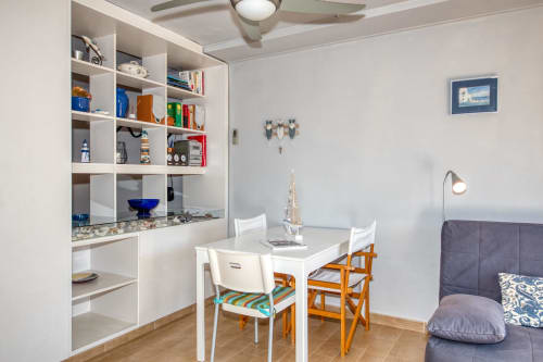 Studio apartment kitchenette and dining area in Palafrugell with white shelving, table, and chairs