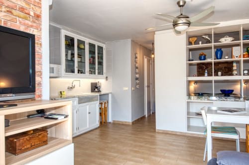 Modern studio apartment kitchenette in Palafrugell with white cabinetry, granite countertops, stainless steel appliances, and