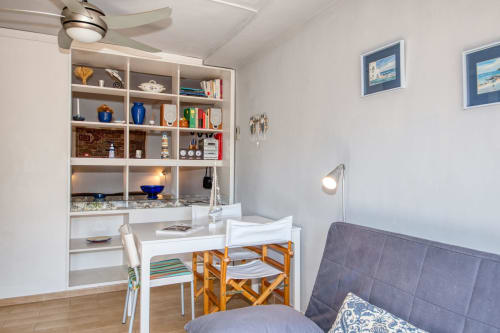 Modern studio apartment in Palafrugell with workspace, shelving, desk, chairs, and blue upholstered bed