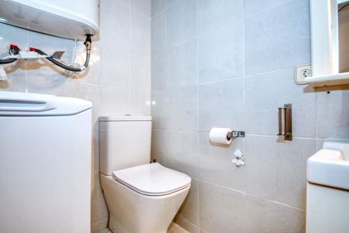 Modern bathroom in Palafrugell apartment with white toilet, sink, and light blue tiled walls