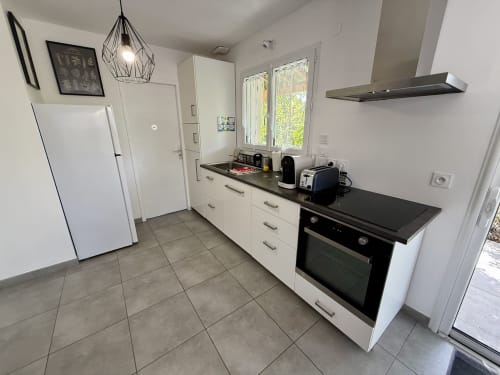 Cucina moderna al Gîte Grange Debout, dotata di forno in acciaio inox, cappa, frigorifero bianco e piano di lavoro nero.