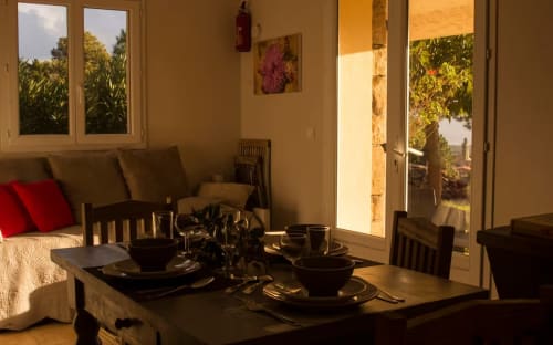 Salle à manger Vista D'oro à Monacia d'Aullène avec table dressée et vue sur mer par les portes vitrées