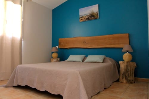 Chambre turquoise lumineuse à Vista D'oro avec lit en bois, photo vue mer et équipements modernes