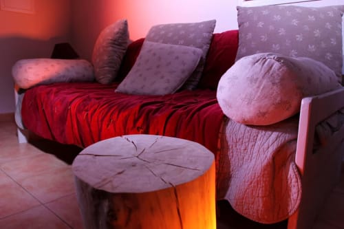 Chambre accueillante à Vista D'oro avec literie rouge, oreillers violets, table de nuit en bois et éclairage ambiant à Monacia d'Aullène