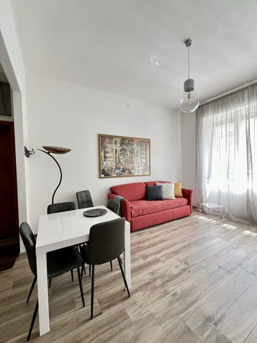Moderno appartamento Puzzle House a Viareggio con tavolo da pranzo, divano rosso, lampada a sospensione e vista sulla città
