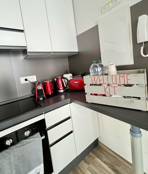 Cucina moderna nell'appartamento La Home Puzzle House di Viareggio, con elettrodomestici rossi, banconi neri, armadi bianchi e atmosfera accogliente