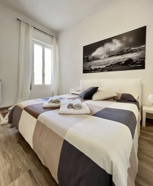 Camera da letto moderna nell'appartamento Puzzle House a Viareggio con biancheria rigata, testata bianca e arte murale in bianco e nero