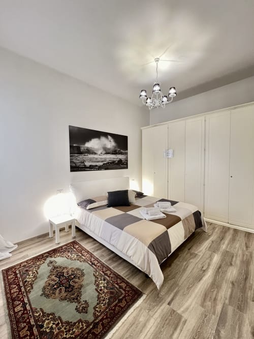 Camera moderna alla LA Home Puzzle House di Viareggio con letto matrimoniale, armadio, lampadario e arte murale in bianco e nero