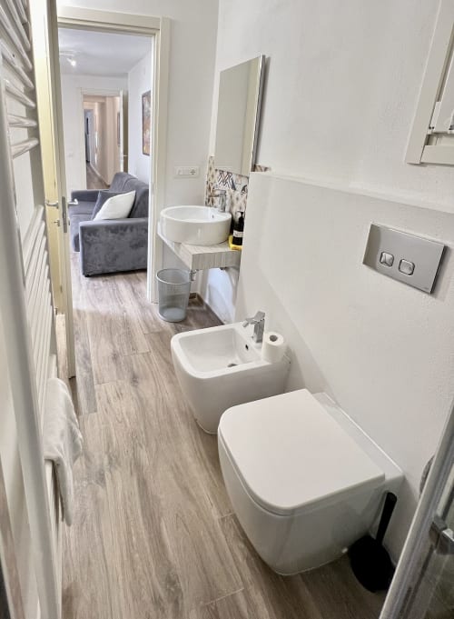 Bagno moderno nell'appartamento LA Home Puzzle House a Viareggio, con toilette bianca, lavabo e specchio vanity