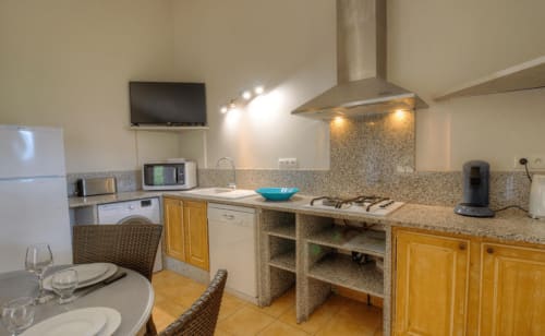 Cuisine moderne à Vista D'oro à Monacia d'Aullène avec plans de travail en granit, placards en bois et électroménagers en acier inoxydable