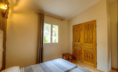 Chambre lumineuse à Vista D'oro avec lit rayé, armoire en bois, vue sur mer par la fenêtre et éclairage naturel