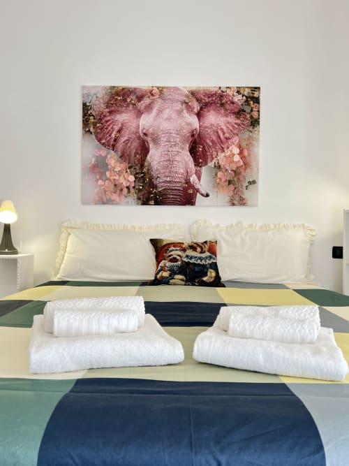 Camera moderna alla LA Home Viareggio con opera d'arte di elefante sopra il letto, asciugamani bianchi e biancheria da letto a righe colorate
