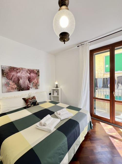 Camera da letto colorata della LA Home a Viareggio con biancheria a righe, opera d'arte con elefante e accesso al balcone