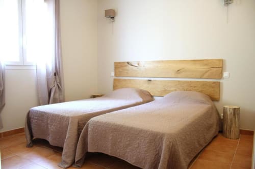 Chambre twin de l'hôtel Vista D'oro à Monacia d'Aullène avec tête de lit en bois et vue mer
