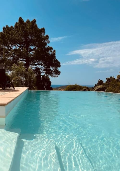 Piscine à débordement avec vue sur la mer Méditerranée à Vista D'oro, Monacia d'Aullène, pins et ciel bleu dégagé