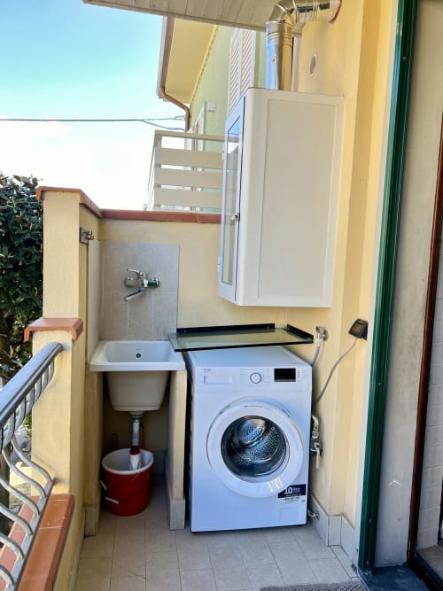 Compatta lavanderia con lavatrice e lavello di servizio nell'appartamento LA Home di Viareggio