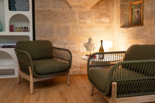 Modern lounge seating area at Pavillon Des Millesimes with olive armchairs, stone walls, and warm lighting in Lussac