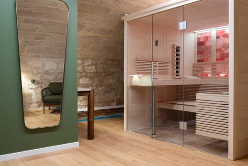 Modern sauna room at Pavillon Des Millesimes SPA with glass doors, wooden interior, and wall mirror in Lussac