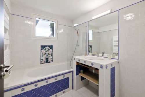 Modern bathroom with blue and white tile accents, bathtub, vanity sink, and shower at Villa Ongizatea in Urrugne