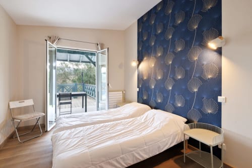 Modern bedroom with blue patterned accent wall, queen bed, and glass doors opening to mountain-view terrace at Villa