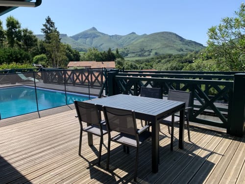 Outdoor dining table on wooden deck with private pool and mountain views at Villa Ongizatea, Urrugne