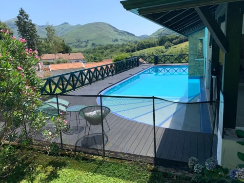 Piscina azul brillante de Villa Ongizatea B&B en Urrugne, con vistas a la montaña, asientos en la terraza y paisaje pastoral