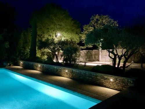 Verlicht zwembad 's nachts met stenen muur en aangelegde tuinen bij Provence Km28 in Gordes