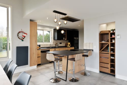Modern kitchen and dining area in Villa Ongizatea cottage with wooden cabinetry, black countertop, pendant lights, and bar