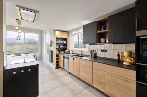 Modern kitchen with black and natural wood cabinetry, mountain views, dining area in Villa Ongizatea cottage, Urrugne
