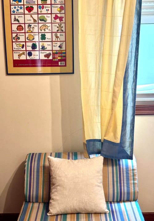 Sillón a rayas con cojín crema en apartamento Holibai, Baiona, con abecedario español en pared