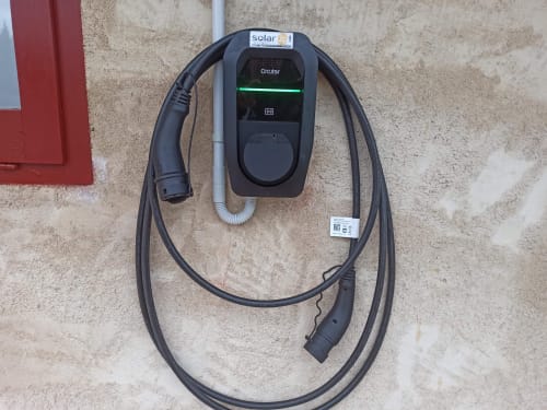 Station de recharge solaire pour véhicules électriques sur mur ancien à Can Gat Vell, Girona