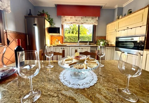 Amplia zona de cocina-comedor en la cabaña Holibai con encimera de granito, copas de vino, aperitivos y vistas a la montaña