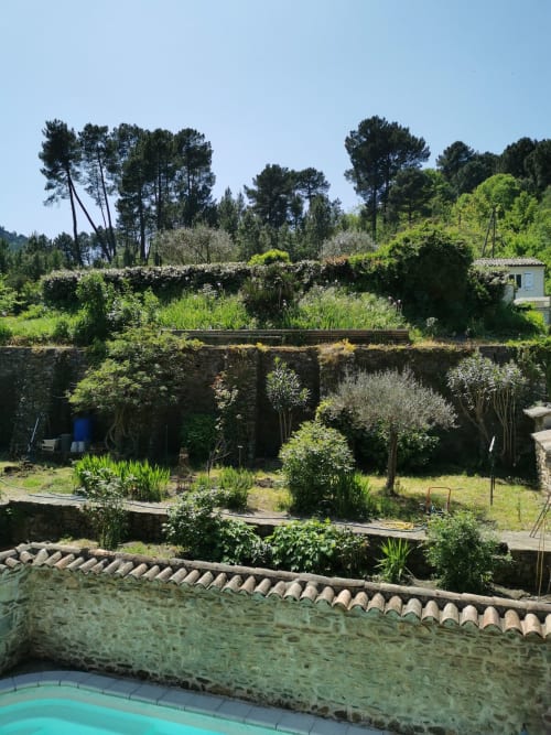 Vista della piscina con giardini terrazzati, muri in pietra, siepi verdi e paesaggio mediterraneo presso Chambre d'hôtes Gîte Le