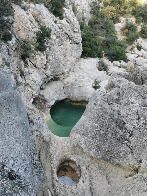 Piscina color smeraldo circondata da rocce calcaree con scarsa vegetazione a Le Martinet, Francia