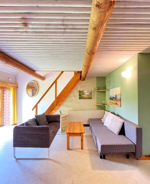 Spacieux loft à La Ferme De Werpin avec poutres en bois, deux canapés, mur d'accent vert et équipements modernes
