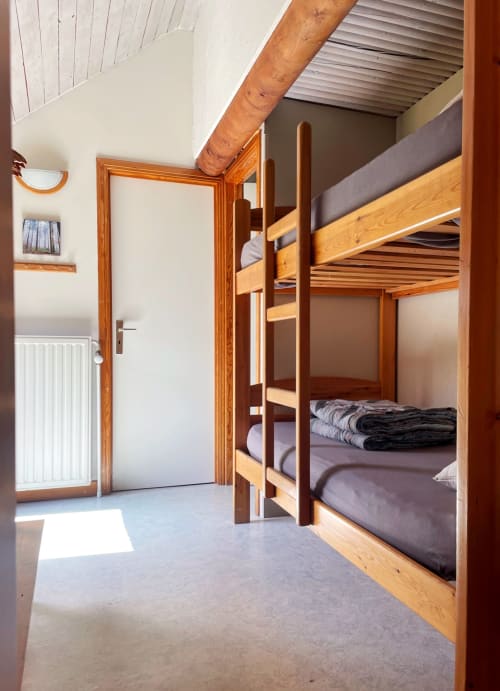 Chambre spacieuse avec lits superposés en bois, murs blancs et lumière naturelle à La Ferme De Werpin, Hotton