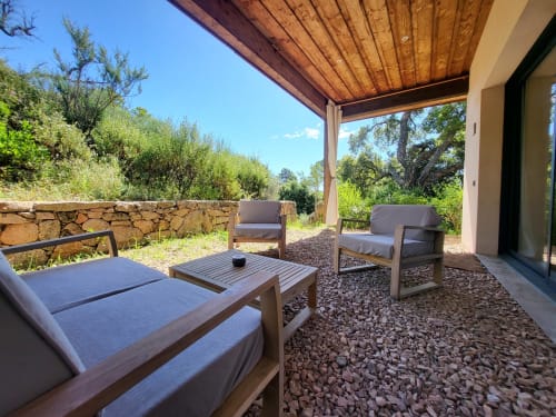 Outdoor lounge area at Villas Lantana villa in Lecci with wooden chairs, coffee table, stone patio, and mountain views under