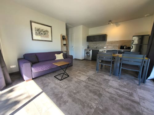 Modern 38m² villa at Villas Lantana in Lecci with purple sofa, kitchenette, dining area, and tile flooring