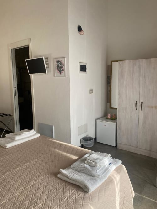 Camera luminosa della Corte Sicula B&B a Siracusa con letto, armadio, frigobar e arredamento minimalista