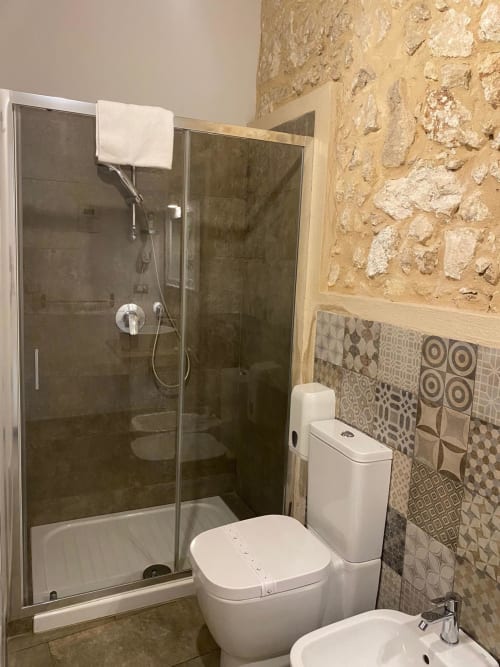 Bagno moderno della Corte Sicula B&B a Siracusa con doccia, toilette e piastrelle decorate