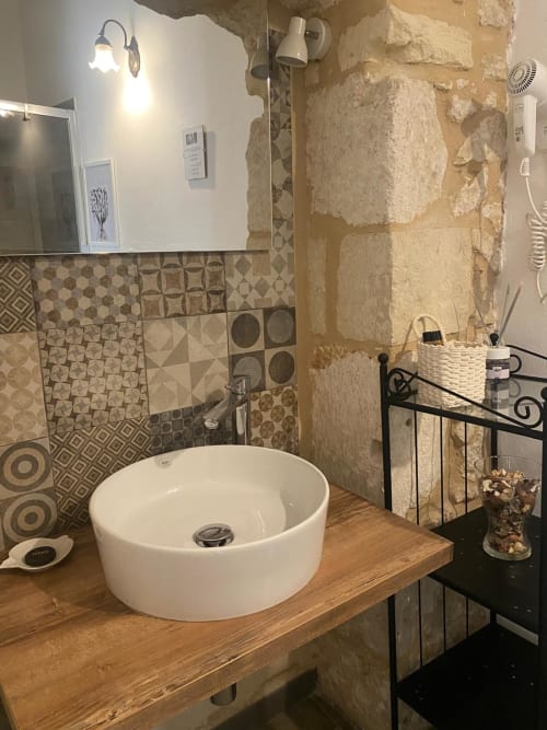 Bagno moderno della Corte Sicula B&B a Siracusa con lavabo rotondo bianco su piano in legno e piastrelle decorate
