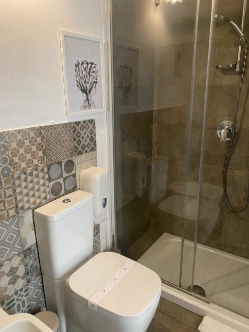 Bagno moderno presso la Corte Sicula B&B a Siracusa con doccia walk-in, piastrelle decorate e opera d'arte lavanda