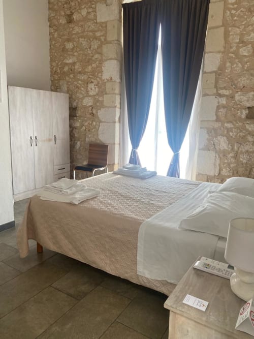 Camera rustica a Corte Sicula B&B a Siracusa con muri in pietra, tende blu e arredamento tradizionale