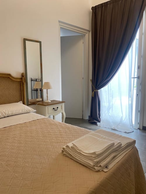 Camera elegante alla Corte Sicula B&B di Siracusa con letti gemelli, specchio, comodino e porte drappeggi blu