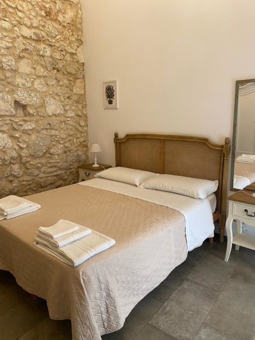 Camera rustica in pietra al Corte Sicula B&B di Siracusa con letto in legno e biancheria bianca